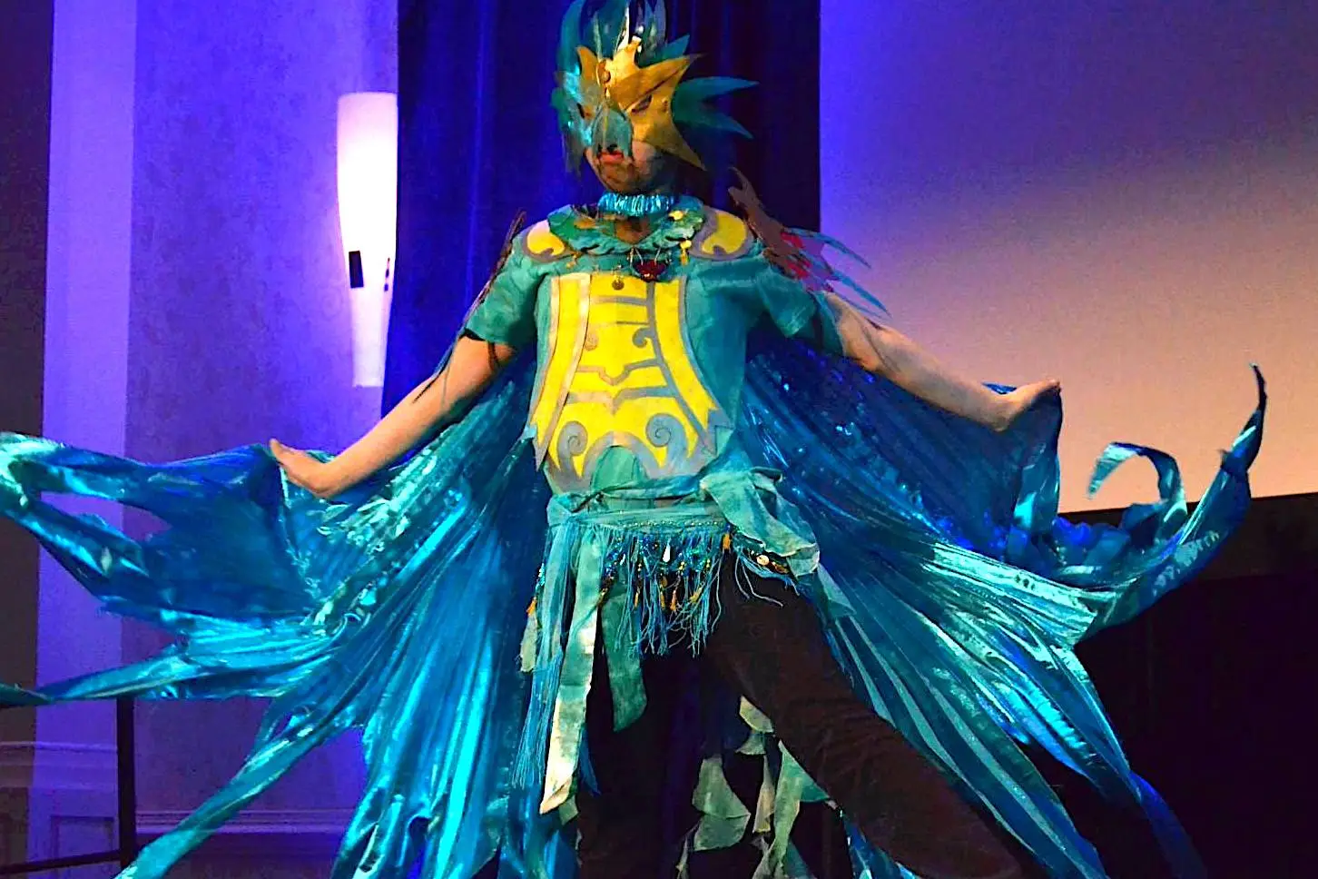 Cosplay/masquerade picture of someone in a brightly colored blue and yellow bird-like costume